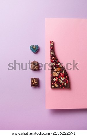 Handmade chocolates and a flatlay natural chocolate bar. Creative design of sweets and desserts on a pink and purple background.