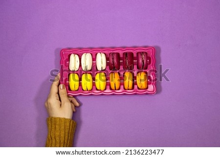 closeup hand woman holding a box of French colorful Macarons Cookies