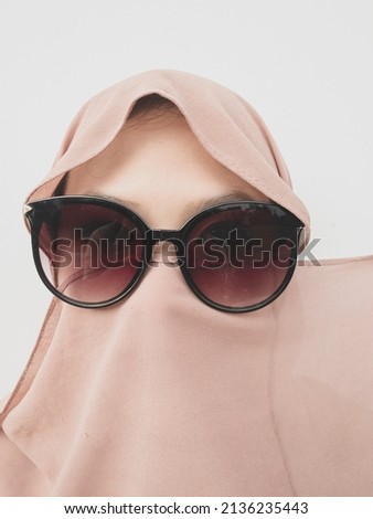 young asian beautiful woman wearing pink hijab and sunglasses isolated on white background