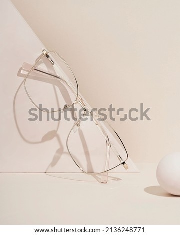 Women's glasses on beige background. The product still a life concept. Minimal still life. Royalty-Free Stock Photo #2136248771