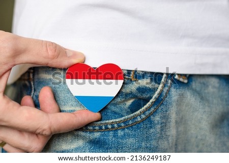 Patriot of the Luxembourg! Wooden badge with Luxembourg flag in the shape of a heart in a man's hand.
