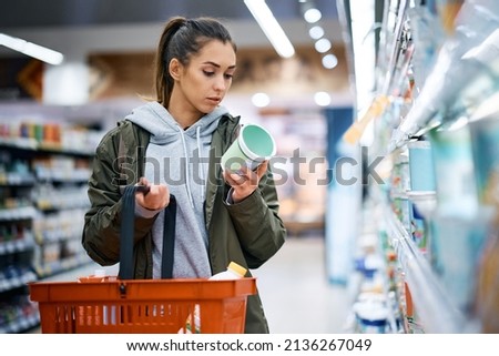 Young woman buying diary product and reading food label in grocery store. Royalty-Free Stock Photo #2136267049