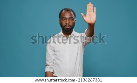 African american model raising palm to advertise stop sign in studio, expressing denial and refusal. Young adult showing rejection gesture with hand, denying access abnd feeling displeased.
