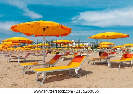 Bright orange parasols and deck chairs on the beach in Rimini, Italy.  Royalty-Free Stock Photo #2136268055