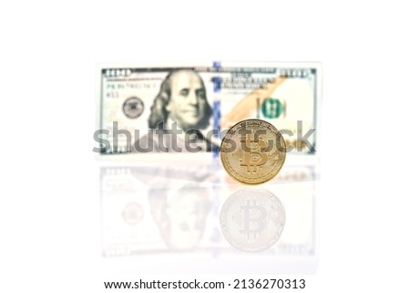 Gold bitcoin coin standing in front of dollar bills