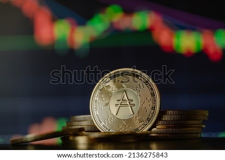 Stack or heap of gold Cardano ADA cryptocurrency with candle stick graph chart and digital background. Royalty-Free Stock Photo #2136275843