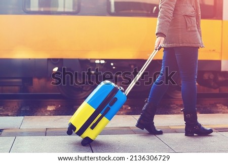 A refugee from Ukraine is fleeing Russian aggression against Ukraine. A suitcase in the color of the Ukrainian flag. Flight to Europe from the war. Royalty-Free Stock Photo #2136306729