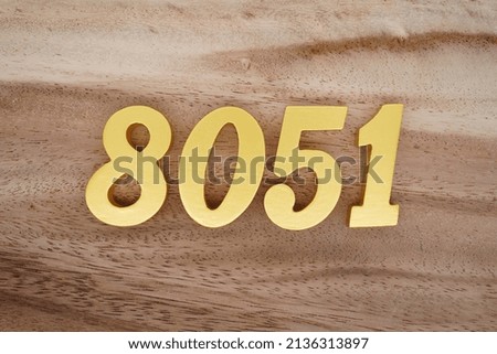 Wooden  numerals 8051 painted in gold on a dark brown and white patterned plank background.