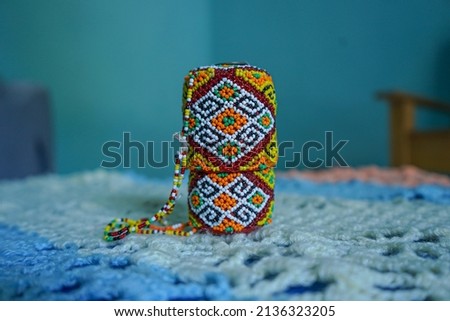 an object decorated with beads on a blue background