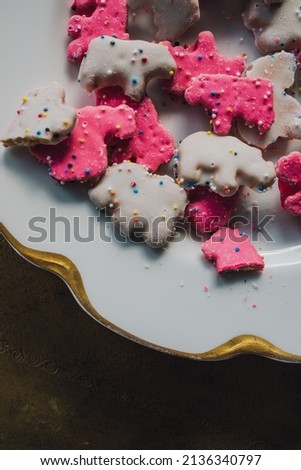 frosted Circus Animal Cookie Pink and White Sprinkled Animal Crackers on white and gold plate. copy space.