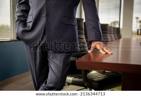 Close up of businessman in suit resting his hand on a conference room table  Royalty-Free Stock Photo #2136344713