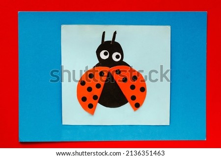 Top view of papercraft ladybug made by child on multicolor sheets background