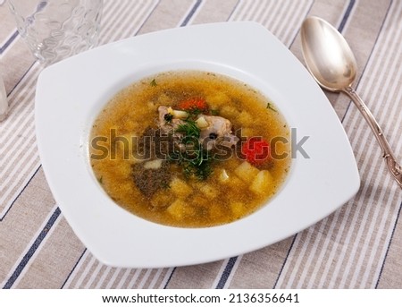 Appetizing soup in pork broth with potatoes, carrots and onions seasoned with herbs. Comfort food .