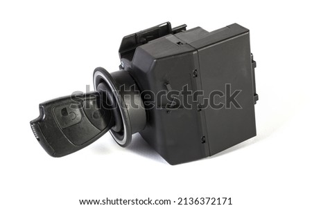 Electronic ignition lock with a key and a button made of black plastic on a white isolated background in a photography studio, a spare part for car repair or for sale in junk yard.