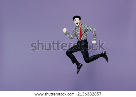 Full size body length side view profile excited young mime man with white face mask wears striped shirt beret run look camera hurry up isolated on plain pastel light violet background studio portrait