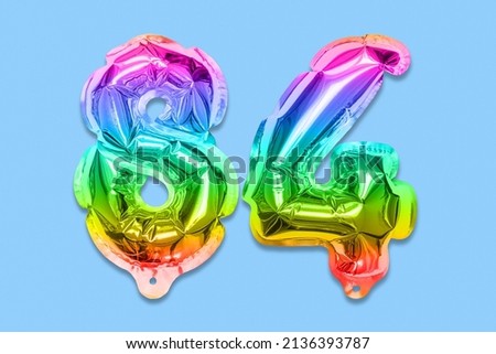 Rainbow foil balloon number, digit eighty four on a blue background. Birthday greeting card with inscription 84. Top view. Numerical digit. Celebration event, template.