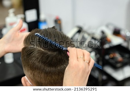 Hairdresser puts hair to teen boy after haircut, haircut for teen, styling after haircut with gel and comb. Royalty-Free Stock Photo #2136395291