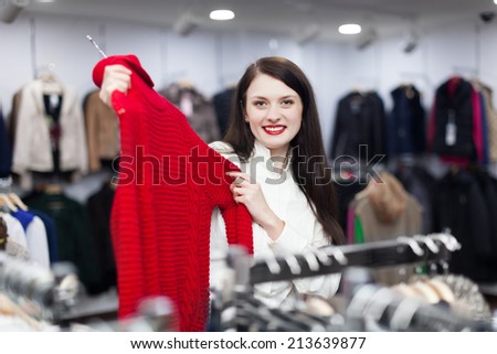 Ordinary woman choosing sweater at clothing store