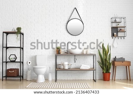Stylish interior of restroom with toilet bowl, modern sink and holder with toilet paper rolls Royalty-Free Stock Photo #2136407433