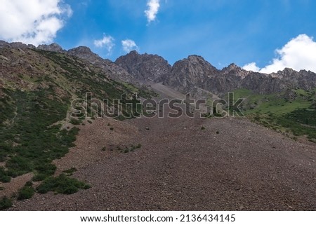 Rockslide in the mountains. Scenic background. Natural summer landscape. Beautiful mountains with landslide. Barskoon river valley. Travel, tourism in Kyrgyzstan concept. Sarymoinak river.