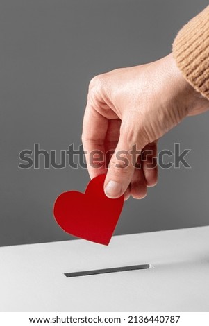 charity, love and valentine's day concept - close up of hand putting red heart into donation box Royalty-Free Stock Photo #2136440787