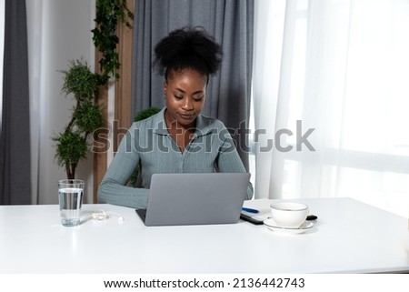 Young concentrated African American woman blogger and human rights activist writing a blog about cyber bullying and racism among young people through her personal negative experience. Royalty-Free Stock Photo #2136442743