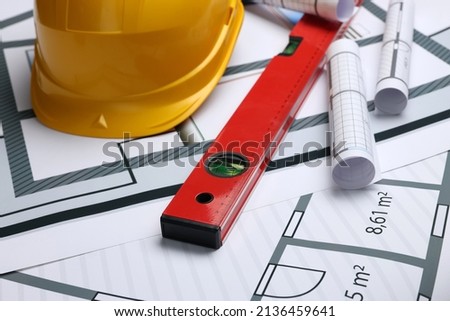 Construction drawings, safety hat and bubble level on house plan, closeup