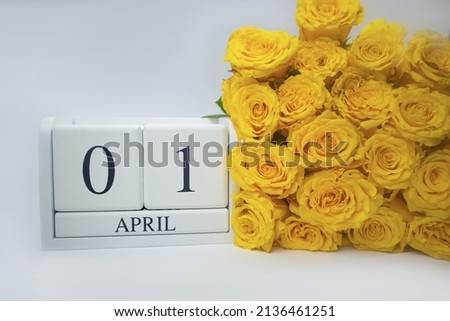 Wooden calendar April 1 and yellow roses on a white background. The concept of a holiday, April Fool's Day, a plan, an important event. High quality photo