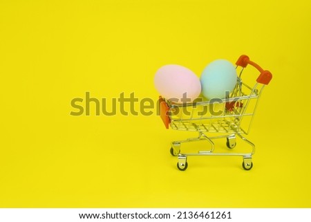 Easter . Shopping cart with Easter eggs on a yellow background. The concept of a holiday, promotion, products, shopping, sale, discounts, gifts. High quality photo