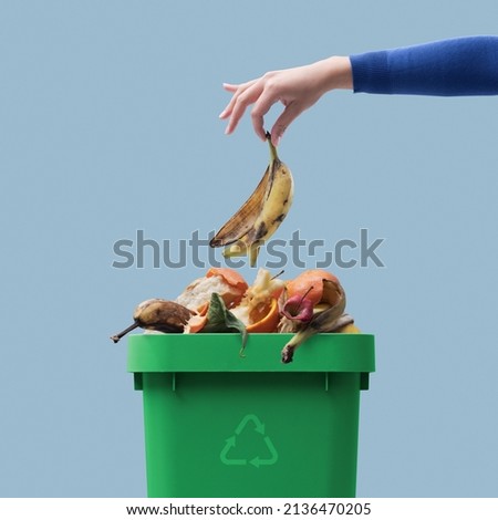 Woman putting organic biodegradable waste in a recycling bin, separate waste collection concept Royalty-Free Stock Photo #2136470205