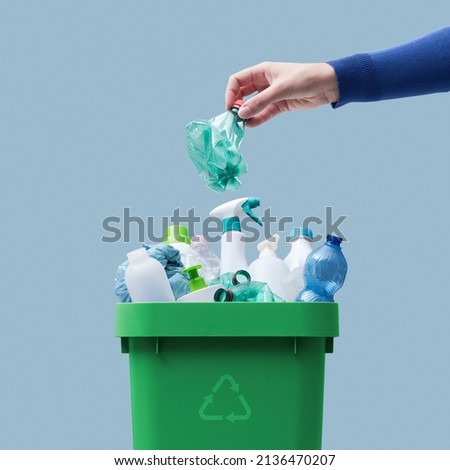 Woman putting a plastic bottle in a full recycling bin, separate waste collection concept Royalty-Free Stock Photo #2136470207