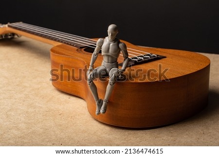 The man is sitting on the ukulele. Music in our hearts. On a dark background.