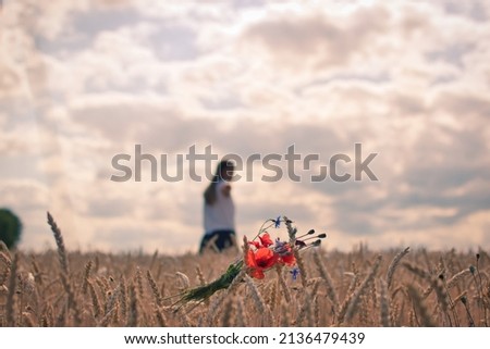 Girl in the field has to leave loved ones behind, longing, saying goodbye is difficult, there is a bouquet in a field and a woman looks back Royalty-Free Stock Photo #2136479439