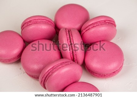 Macarons closeup on white wooden background. Sweet and colourful pink french macaroons. Cooking at home. 
