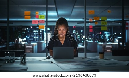 Portrait of African American Businesswoman Working on Laptop Computer in Big City Office Late in the Evening. Female Executive Director Managing Digital e-Commerce Project, Finance Analysis Royalty-Free Stock Photo #2136488893