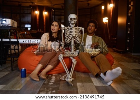 Funny couple and skeleton watching studio projector