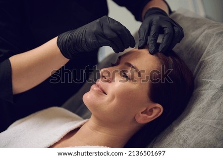Close-up of a happy middle aged beautiful woman taking care of her face skin in modern wellness spa salon. Anti-aging anti wrinkles and rejuvenating beauty treatment. Health care and medicine concept Royalty-Free Stock Photo #2136501697