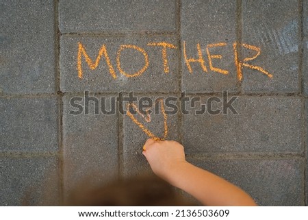 Cute boy draws the word mother with chalk. The boy loves his mother. Can be used as a postcard for the mother. Happy Mother's day