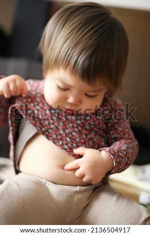 Young toddler discovering her belly button. Royalty-Free Stock Photo #2136504917