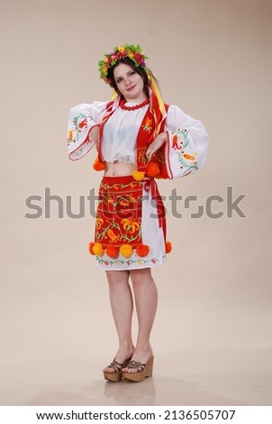 A girl in a folk Ukrainian costume on a white background. Girl in a wreath of flowers, in a folk shirt, skirt, apron