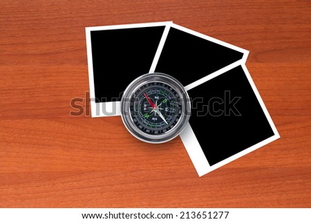 Blank, black picture frames with compass on wooden table.