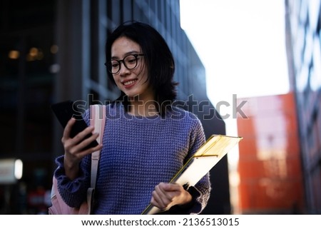 Beautiful Chinese woman with mobile phone walking on the street. Young girl typing a message