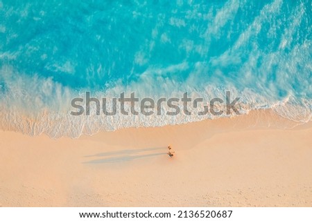 Aerial view of amazing beach with couple walking in sunset light close to turquoise sea. Top view of summer beach landscape, romantic inspirational couple vacation, romantic holiday. Freedom travel Royalty-Free Stock Photo #2136520687