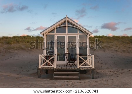 Picturesque beach hut on a North Sea beach in the Netherlands against blue sky at sunset