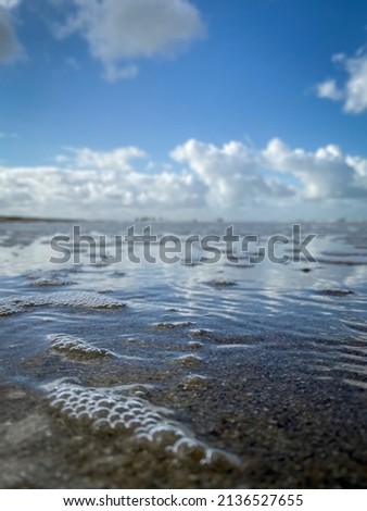 Low angle view of water on a beach with bubbles and blurred background