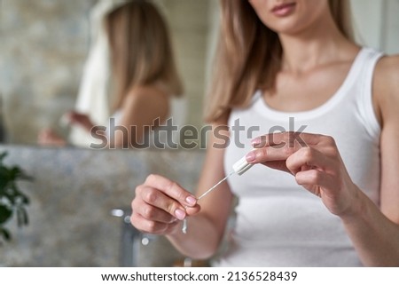 Unrecognizable young caucasian woman standing in the bathroom and holding a tampon  Royalty-Free Stock Photo #2136528439
