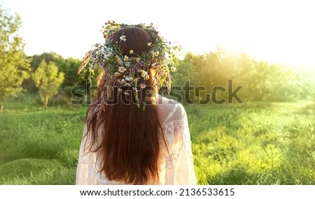 girl in flower wreath on meadow, sunny green natural background. Floral crown, symbol of summer solstice. Slavic ceremony on Midsummer, wiccan Litha sabbat. pagan holiday Ivan Kupala Royalty-Free Stock Photo #2136533615
