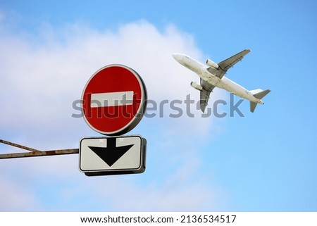 Stop sign with down arrow and airplane in blue sky. Concept of band on flights over Europe from Russia, sanctions due to the russian special military operation in Ukraine Royalty-Free Stock Photo #2136534517