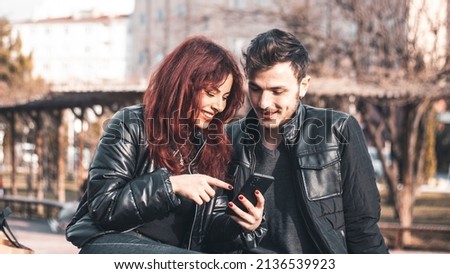 the girl shows her boyfriend something from her smartphone and they're smiling.
