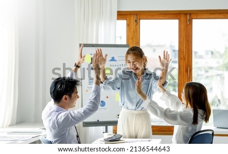 Group of Young Asian business team creative businesspeople coworker in office Happy to be successful partnership teamwork celebrating achievement and success concept. Royalty-Free Stock Photo #2136544643